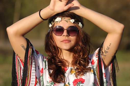 Young woman in hippie style looking at the camera and holding hands on heads