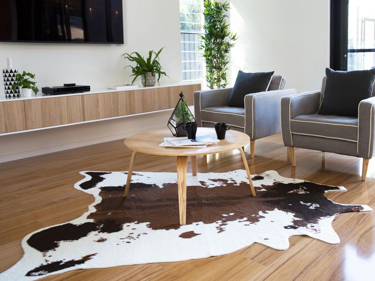 cowhide rugs in a room with wooden table and sofas in it