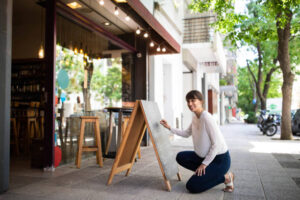 Woman crafting a promotional sign at a liquor store.