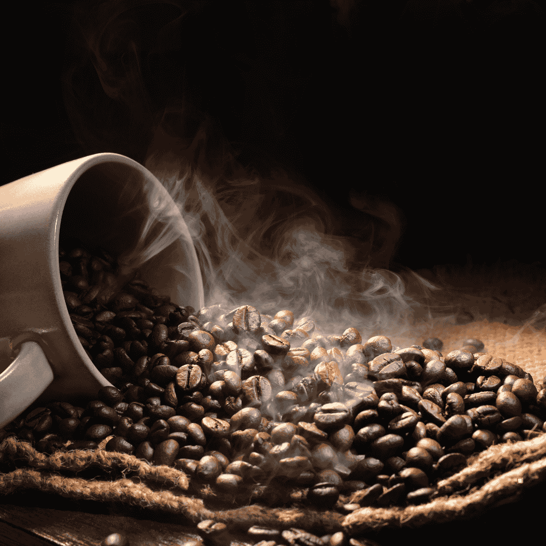 steaming italian roast coffee beans spilling from a cup